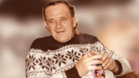 A picture taken of Paul Kirtley's dad, before he died at the age of 61, standing behind a sofa wearing a jumper. 