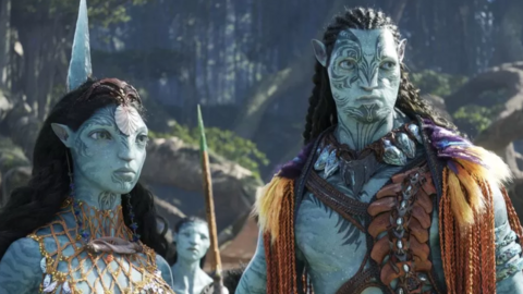 Two members of the Metkayina Clan from the Avatar film, The Way of Water, stand wearing feathers, ropes, straps, and shells