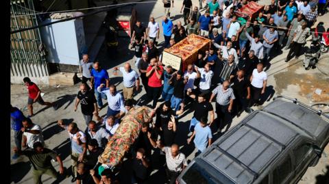 Mourners carry coffins of people killed in Israeli strikes on Saksakiyeh, during a funeral procession, in Sidon, southern Lebanon, 24 September