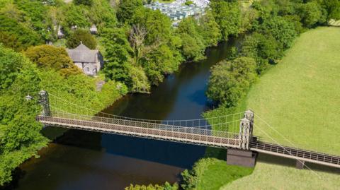 Delwedd wedi'i chynhyrchu gan gyfrifiadur o sut fydd y bont newydd yn edrych. Mae capel a pharc carafannau yn y cefndir.