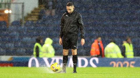 Referee Ruebyn Ricardo tries the bounce test and abandons the game during Blackburn Rovers' Championship fixture with Sheffield Wednesday