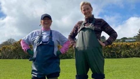 Anna and Pippa standing together smiling in a field in waders.