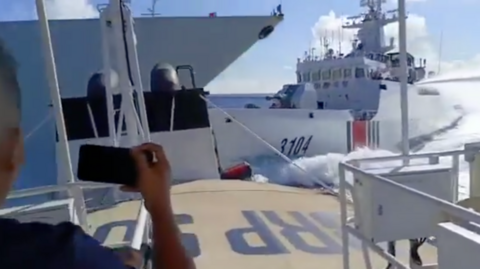 A screenshot from a video showing a Chinese coast guard vessel on the right, hitting a larger ship on the left. The video is filmed from a third vessel