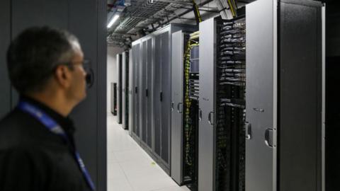 Server room at the Yotta data centre in Navi Mumbai, India, with a spectacled employee pictured on the left.