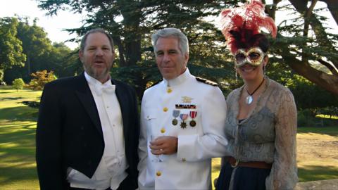 Harvey Weinstein, Jeffrey Epstein and Ghislaine Maxwell are pictured standing on the lawn at Royal Lodge on the royal estate in Windsor with trees in the background. All wear fancy dress with Weinstein and Epstein wearing suits and Maxwell is seen wearing a mask.