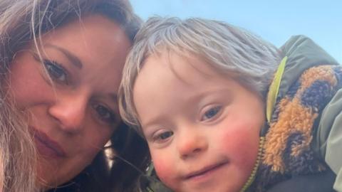 A selfie of Charli, a womanwith long brown hair, and a young blonde boy, they both smile brightly.