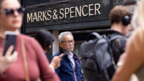 People walking in front of Marks and Spencer store front.