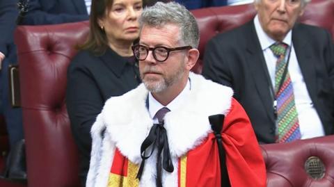 Lord Matthew Doyle wearing a red cloak in the House of Lords during his introduction