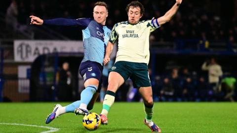 Wycombe Wanderers forward Cauley Woodrow battles for possession with Cardiff City midfielder Ryan Wintle.