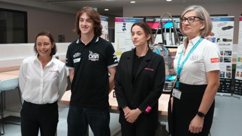 From left to right: Vanina Ickx, a representative of Oxford Brookes Racing, Marta Garcia and an event organiser posing for a picture at the International Women in Engineering Day event. They are looking away from the camera.