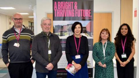 Five people stand in front of a poster reading "a bright & thriving future"