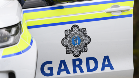 A garda car door. It is open and has the official badge on the side.
