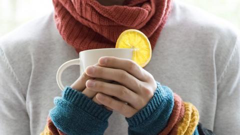 A person holding a mug with a lemon wedge on it.