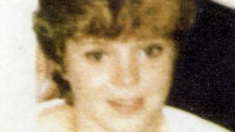 Lynette White, in a blurry photo from the 1980s, is wearing a white top and has short hair 