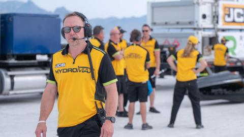 Simon Dowson, from Prodrive, at the Bonneville Salt Flats. He is wearing a yellow JCB Hydromax T-shirt.