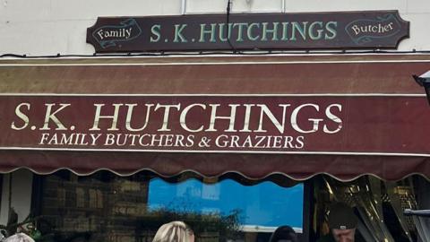 An exterior shot of the front of SK Hutchings butchers in Partridge Green showing shop window frontage and sign.