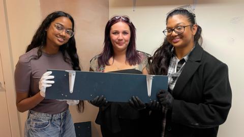 Three young women show the shelf they made at the Skills Hub