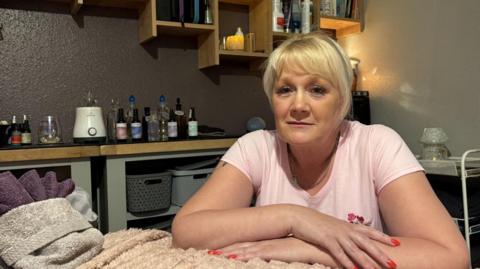 Woman with arms crossed in massage room.