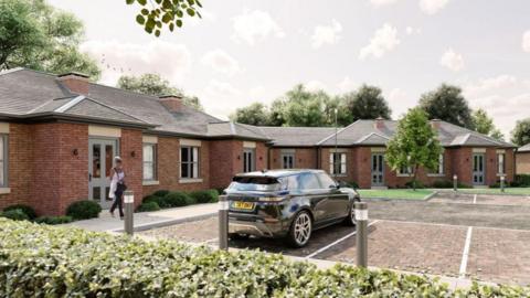 CGI generated image showing a small complex of red brick bungalow with dull grey doors. There is is a lady walking out of one of the doors towards a parked black Range Rover in one of the parking spaces outside the complex.