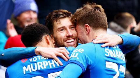 Portsmouth's Callum Lang being embraced by his team-mates after scoring in their 4-1 win over Coventry