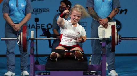 Para powerlifter celebrates after completing a lift at the 2022 Commonwealth Games. She punches the air with her right hand.
