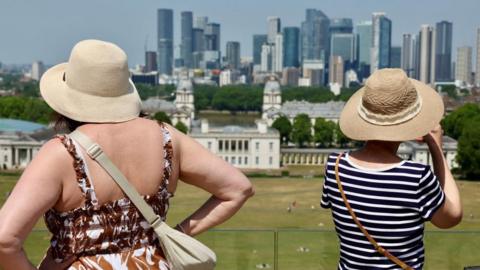 Two women with their backs to the camera looking at a view of sunny London.