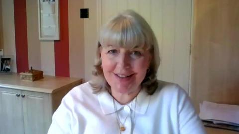 Reverend Lisa Coupland smiles at the camera in a white collared shirt.