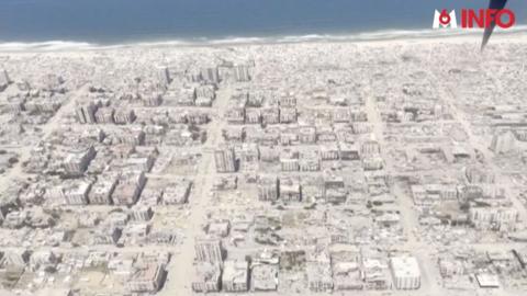 Bombed out buildings and rubble in Gaza, viewed from above, with the coastline visible at the top of the image.