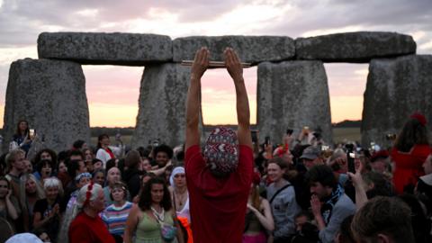 A druid raises her arms above her head as part of a sunrise ceremony at Stonehenge.