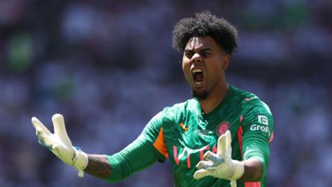 Corey Addai shouting with his hands up while in action for Stockport County