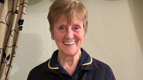 Head and shoulders shot of a smiling Teresa Jackson. She has short light brown hair and is looking into the camera. She is wearing a dark-coloured top.