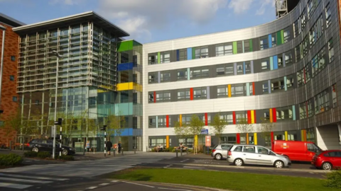 The front of the Queen Alexandra Hospital, a four-storey building with cars parked outside it.