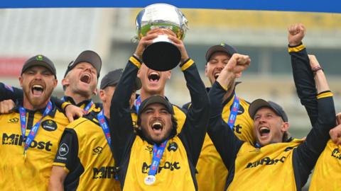 Kiran Carlson of Glamorgan lifts the One Day Cup trophy celebrating with team-mates after beating Somerset in the 2024 final at Trent Bridge