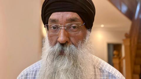 Dabinderjit Singh has a long white beard, glasses and a black turban.