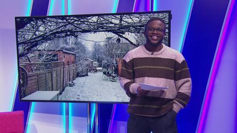 De-Graft in the Newsround studio with a snowy picture in the screen