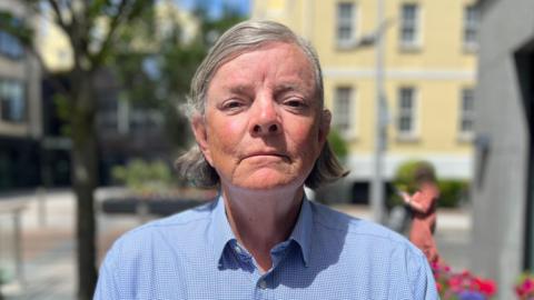 Deputy Charles Parkinson - a man with mid-length grey hair looking towards the camera with a serious face. 

He's wearing a blue shirt. 