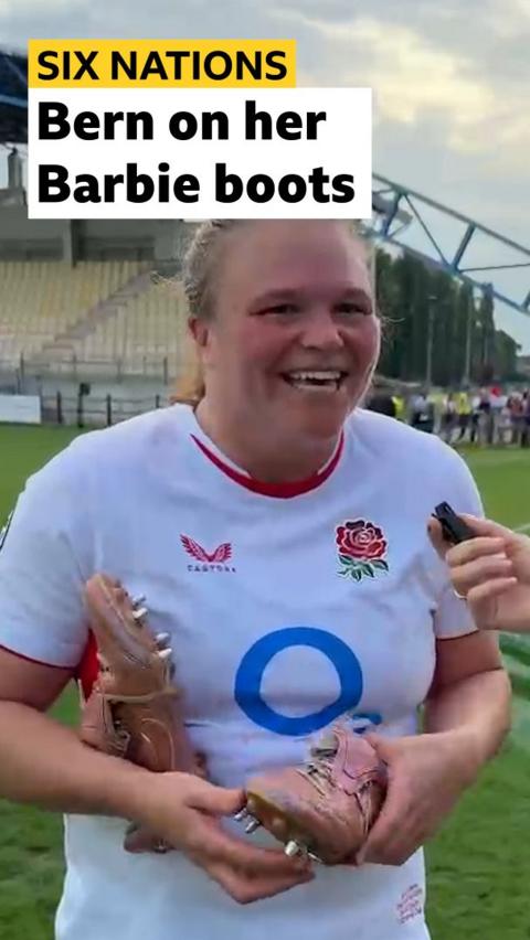 Sara Bern smiling and holding her pink rugby boots 