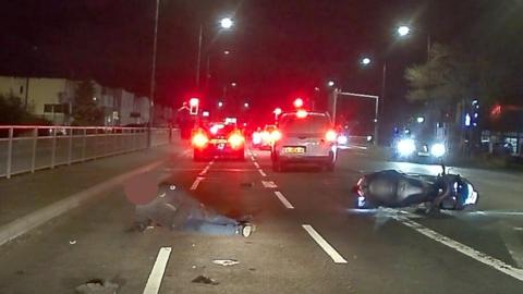 A car following a motorcyclist in the dark before crashing into him