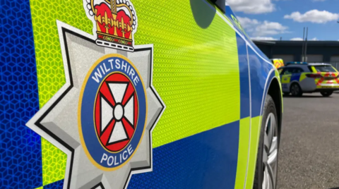 Stock image of a Wiltshire Police badge on the side of a police car