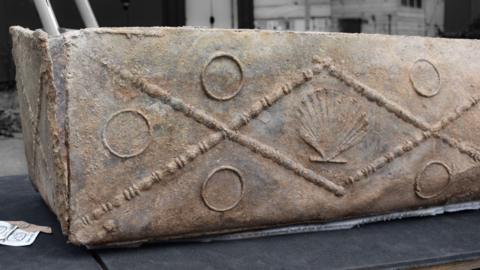 The lead coffin is decorated with a shell and circles embossed on it.