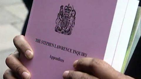 A copy of The Stephen Lawrence Inquiry Appendices held up.