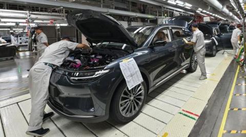 Employees work on an electric vehicle production line at a factory in Jinhua, China