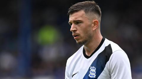 Kai Wagner in action for Birmingham City wearing a white away shirt with a dark blue and black sash.