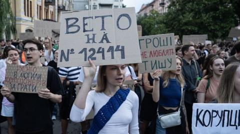 Protesters in Kyiv hold placards against corruption