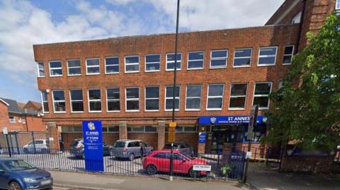 Google Street View of St Anne's school - a late 20th century brick building with three storeys and a flat roof with large sash windows along the two upper floors.