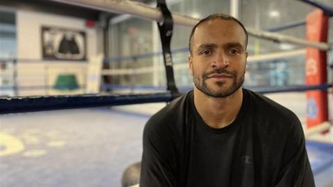 Harlem Eubank sits ringside, wearing a black top.