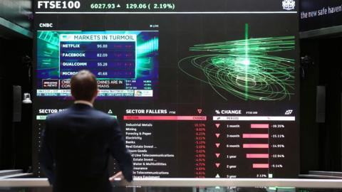 A city worker looks at a stock ticker screen