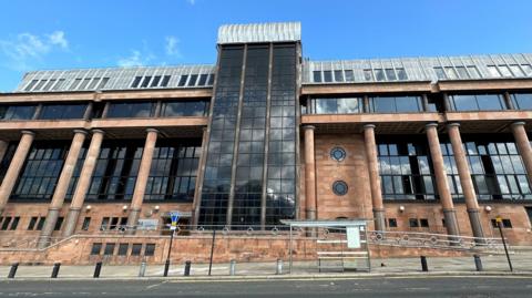 An imposing court building made for red stone and columns with large dark windows