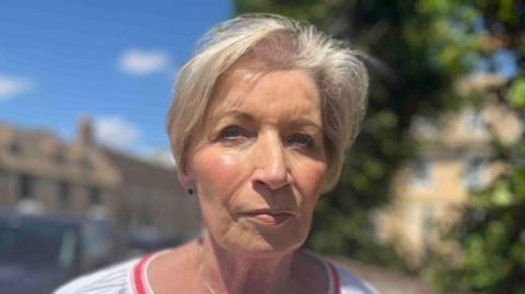 A blond woman wearing a white top 