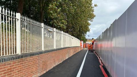 The improved walkway at Botley Road in Oxford, leading towards Frideswide Square, winding by a wall at Oxford Station. Some workers could be seen at the end of it.
